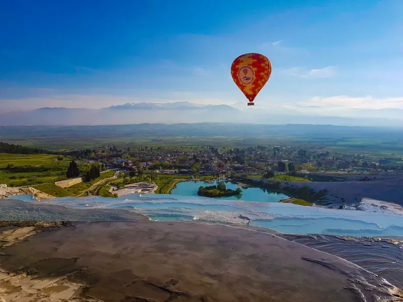 View of Pamukkale's terraces and a hot air balloon