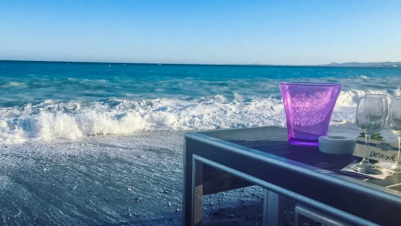 A purple cup sits on a table at Plage Beau Rivage with the Mediterranean Sea as a backdrop - Nice, France
