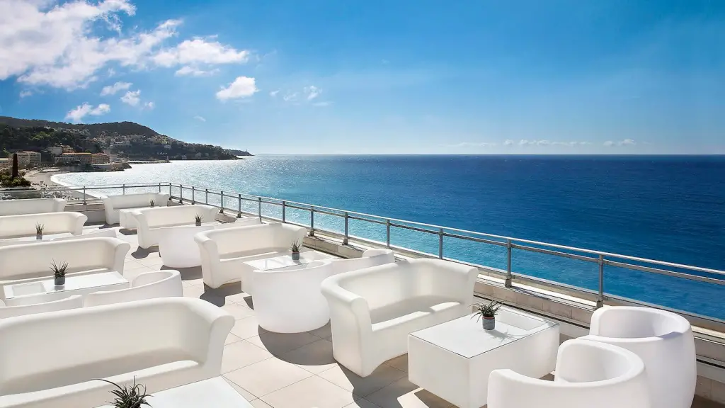 All white sofas and tables on Le Méridien's rooftop with the blue Mediterranean Sea in the background